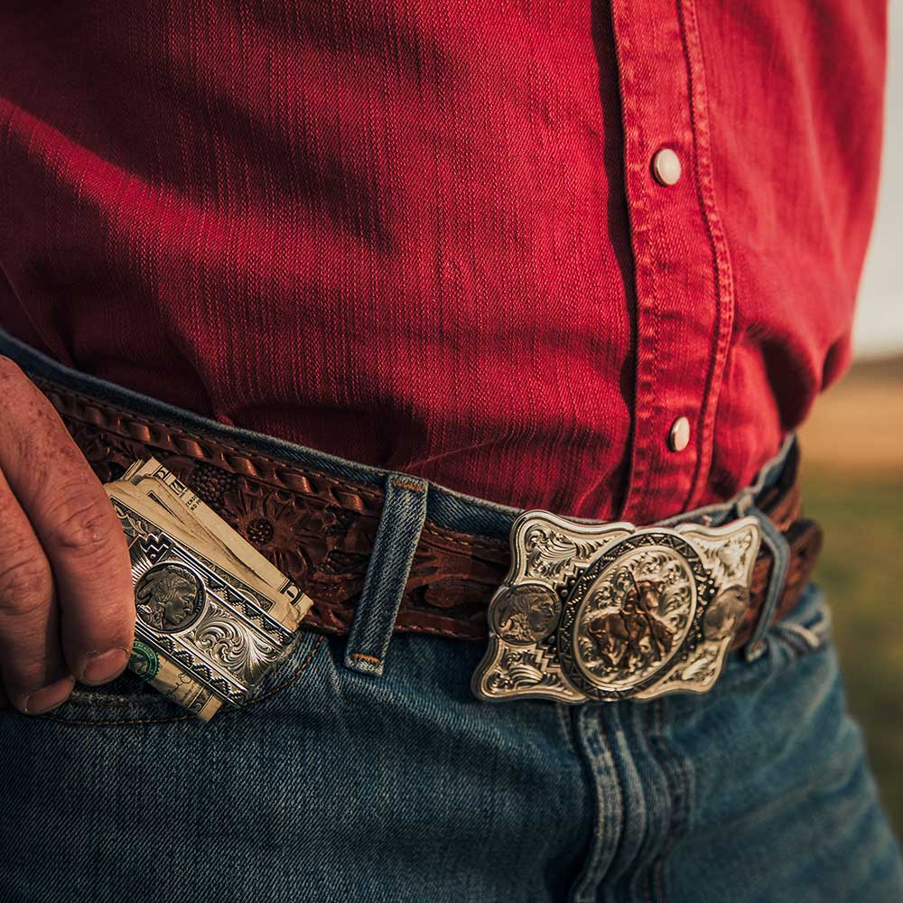 cowboy putting money clip into pocket with belt buckle front and center